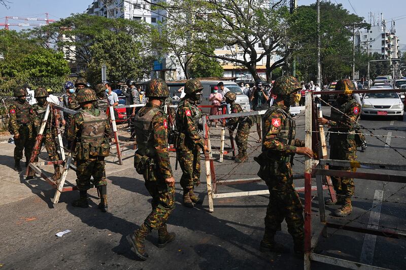 Soldiers prepare to block a road in front of the Central Bank of Myanmar in Yangon on Feb. 15, 2021.