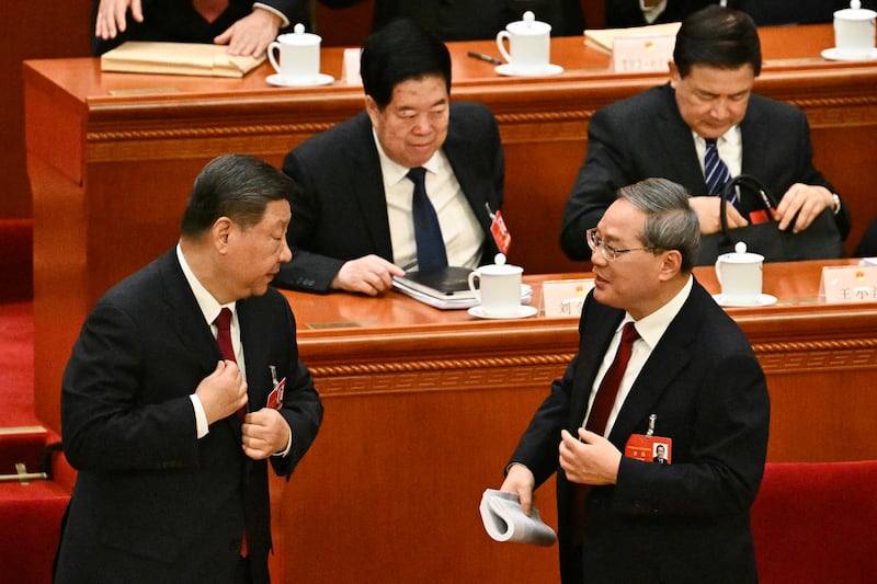 China's President Xi Jinping (L) and Premier Li Qiang leave their seats following the opening session of the National People's Congress (NPC) at the Great Hall of the People in Beijing on March 5, 2025. (Photo by Pedro Pardo / AFP)