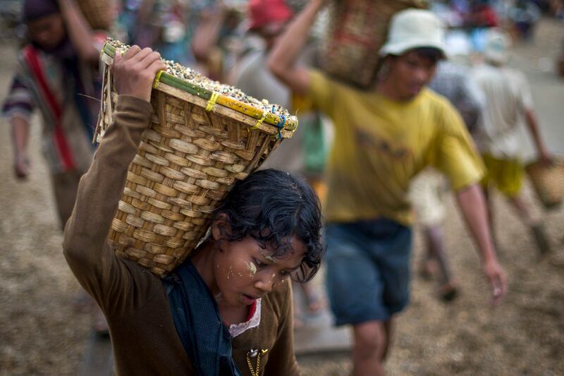 A child carries a basket of stones while unloading a quarry boat with adult workers at a port in Yangon, Myanmar, Sept. 2, 2012. (Alexander F. Yuan/AP)