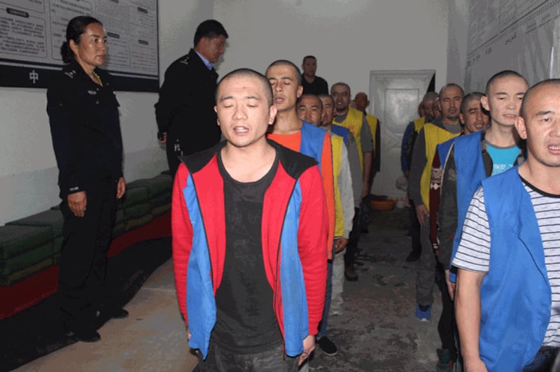 Police guard detainees as they appear to recite words or sing at the Tekes County Detention Center in northwestern China’s Xinjiang region in this image released on May 24, 2022.